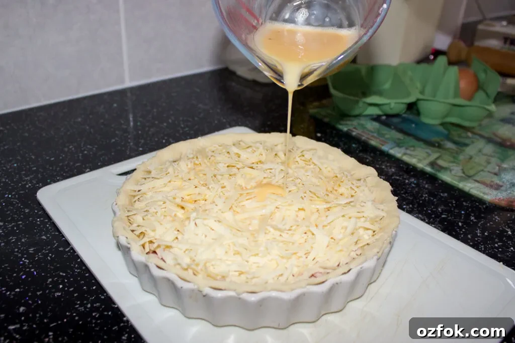 Grandma’s Incredible Ham and Cheese Quiche Recipe 10 Seasoned egg and milk mixture being poured over the quiche