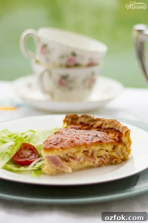 Grandma’s Incredible Ham and Cheese Quiche Recipe 13 A slice of Gran's ham and cheese quiche and a side salad on a white plate.