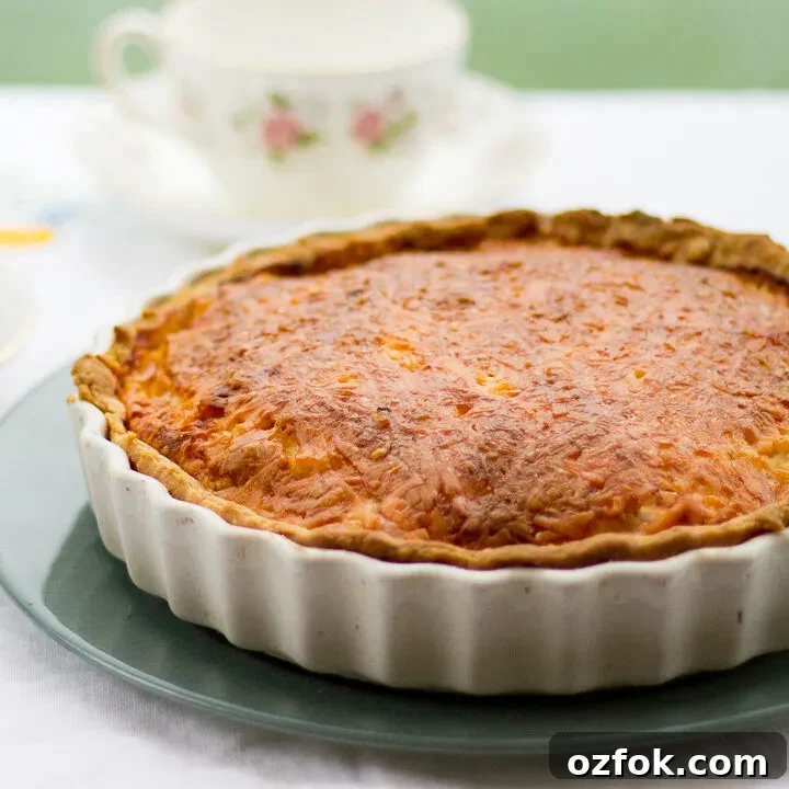 Gran's ham and cheese quiche in a white baking dish on a green plate.