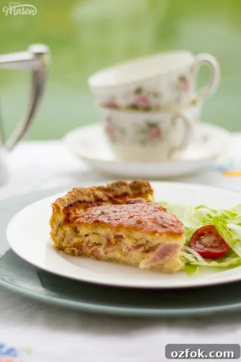 Grandma’s Incredible Ham and Cheese Quiche Recipe 3 A slice of Gran's ham and cheese quiche and a side salad on a white plate set over a larger green plate.