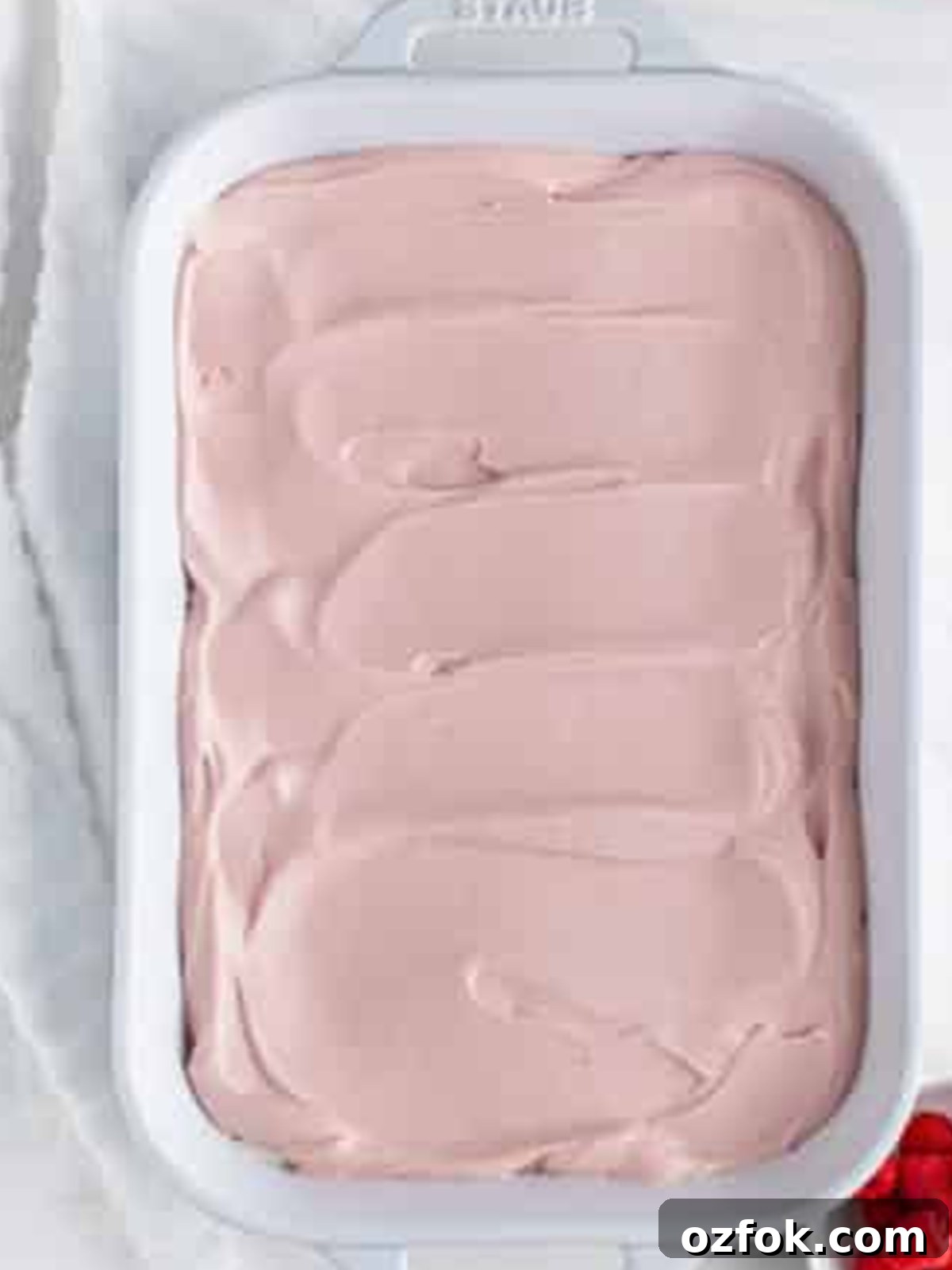 No-Bake Raspberry Icebox Cake Recipe for Summer Parties 11 Pink raspberry preserves whipped cream spread over the crackers for Raspberry Icebox Cake.
