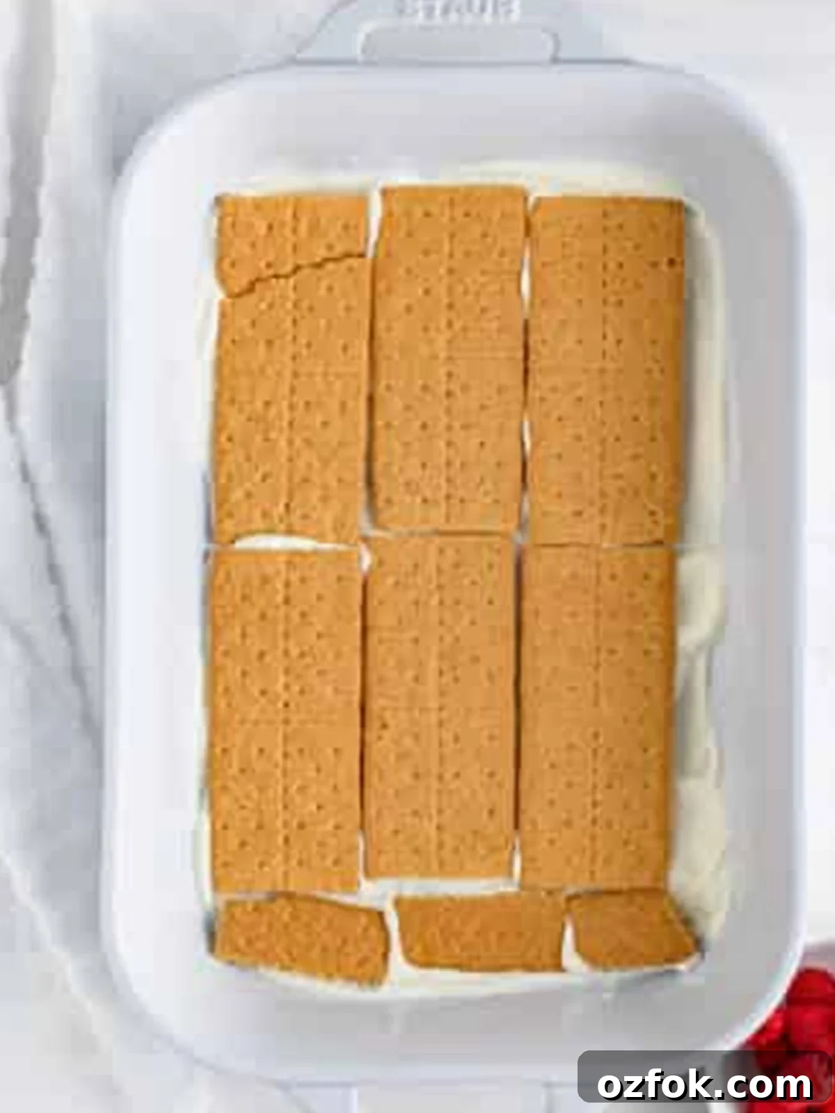 No-Bake Raspberry Icebox Cake Recipe for Summer Parties 8 A single layer of graham crackers covering the cream in the dish for Raspberry Icebox Cake.