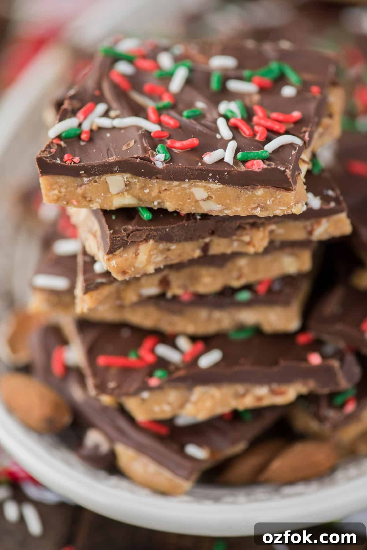 How to make homemade english toffee including directions with and without a candy thermometer. This is the MEGA post on toffee! So many tips, everything you’ve wanted to know about making Christmas toffee at home! english toffee with christmas sprinkles stacked on a white plate