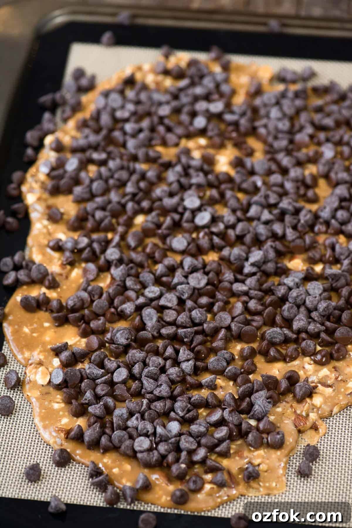Traditional English Toffee Recipe: Crunchy Homemade Toffee in 4 Steps 3 toffee spread out over silicone baking mat with chocolate chips on top