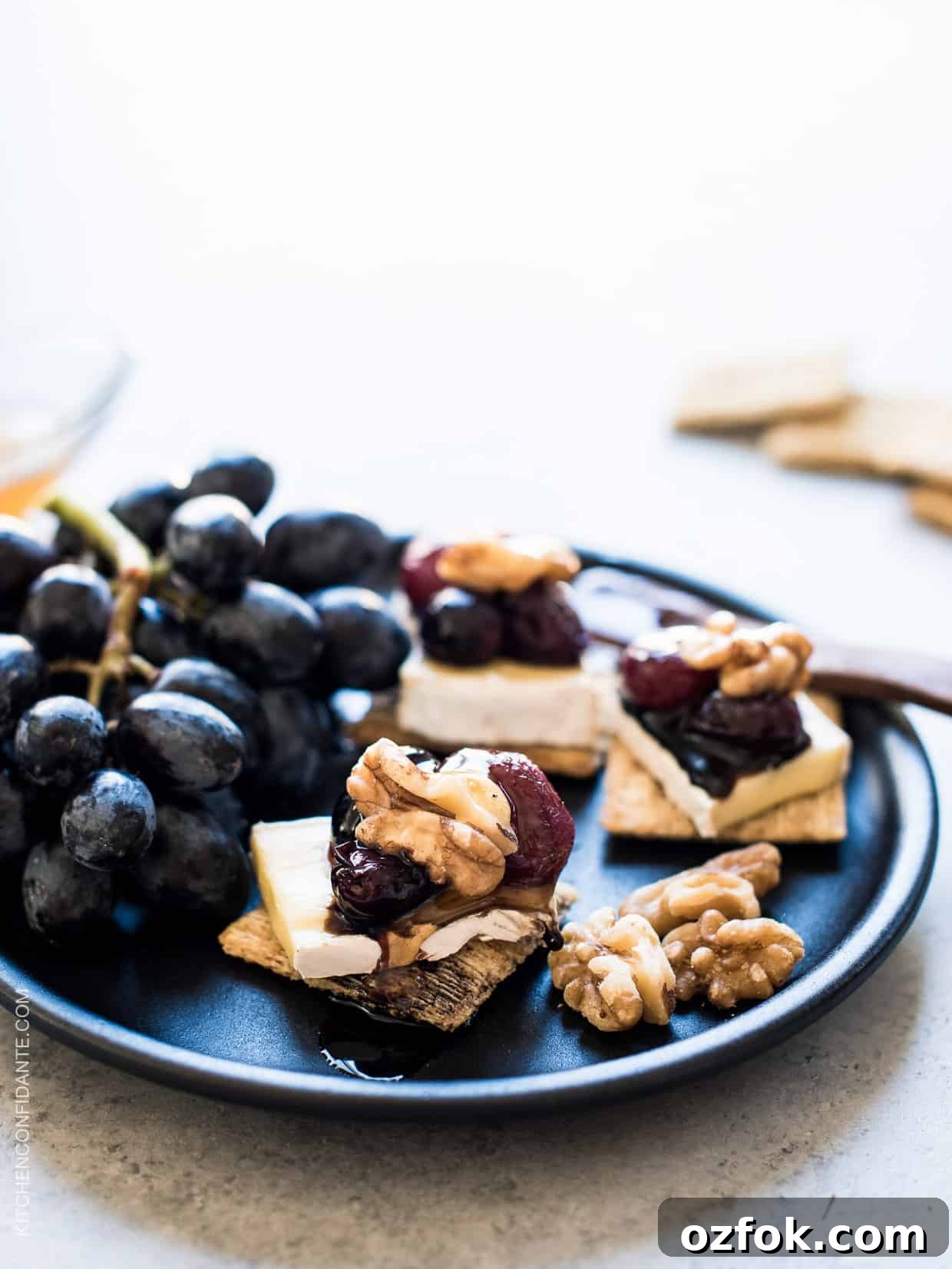 Caramelized Grape, Brie & Walnut Crostini Bites for Entertaining 2 Close up view of Caramelized Grape, Brie and Walnut Bites made with TRISCUIT crackers and served on a plate.
