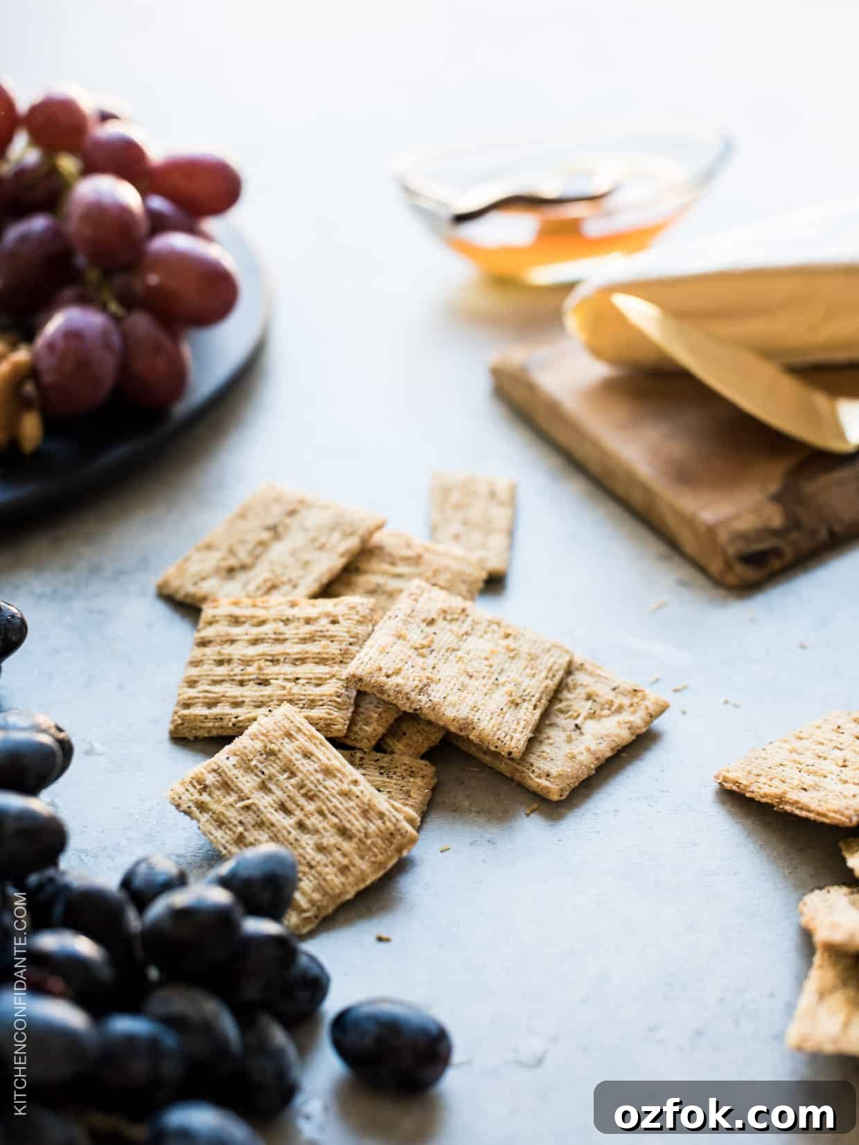 Caramelized Grape, Brie & Walnut Crostini Bites for Entertaining 3 Triscuit crackers and grapes on a rustic surface.