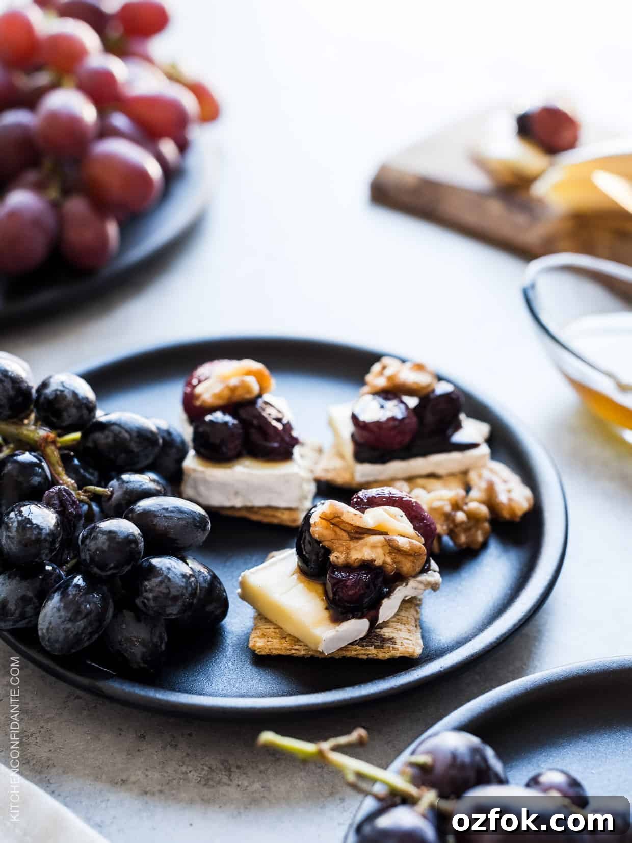 Caramelized Grape, Brie & Walnut Crostini Bites for Entertaining 6 Close up view of Caramelized Grape, Brie and Walnut Bites made with TRISCUIT crackers and served on a plate.