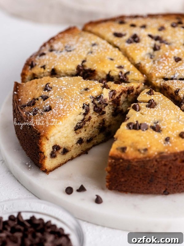 Slices of chocolate chip ricotta cake on a marble cake round with small bowl of mini chocolate chips nearby.