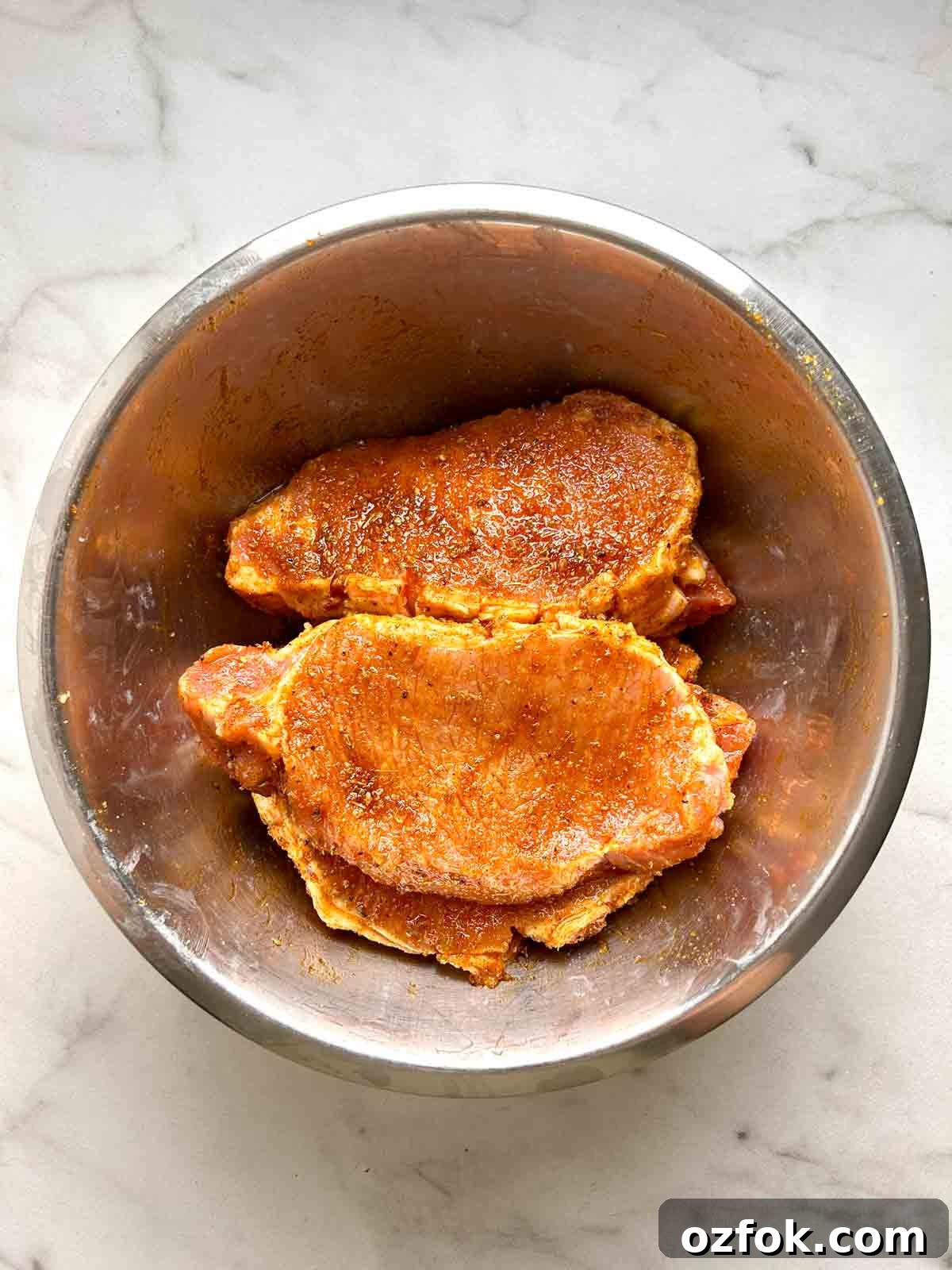 Juicy Oven-Baked Pork Chops with Garlic and Herbs 6 pork chops rubbed with marinade in bowl.