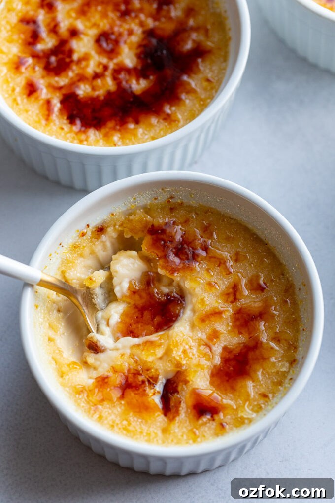 Spooning out a bite of Creme Brulee from a white ramekin.