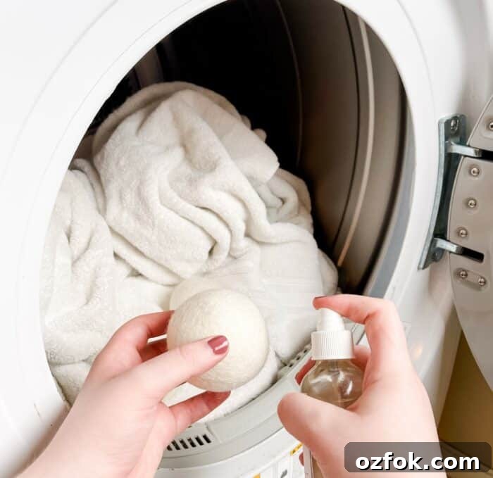 DIY Dryer Ball Spray with Essential Oils for Fresh Laundry 4 spraying dryer ball with essential oil spray before putting wool dryer balls in dryer with laundry