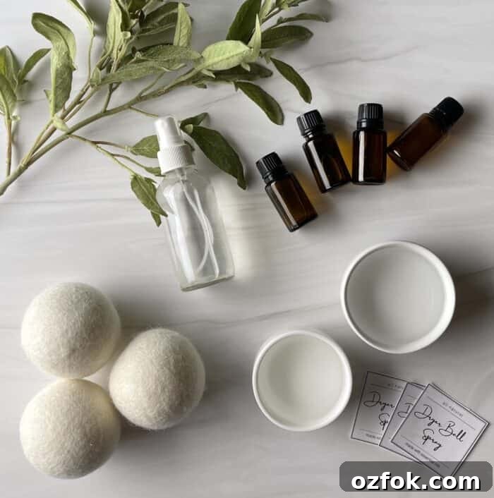 DIY Dryer Ball Spray with Essential Oils for Fresh Laundry 5 supplies to make DIY dryer ball spray - witch hazel, distilled water, essential oils, 4 oz glass spray bottle, free prittable dryer ball spray labels-- next to 3 wool dryer balls and greenery branch