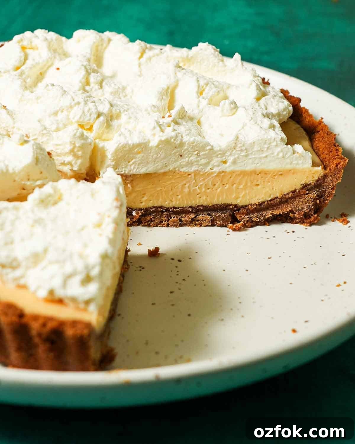 Meyer Lemon Pie with Honey Graham Cracker Crust Recipe 7 A white plate with meyer lemon pie topped with whipped cream on a graham cracker crust.