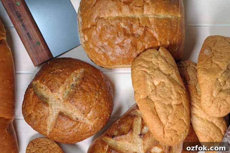 Top Bread Baking Tools Trusted by Foodal 12 Horizontal image of assorted baked goods next to a bench scraper with a wooden handle.