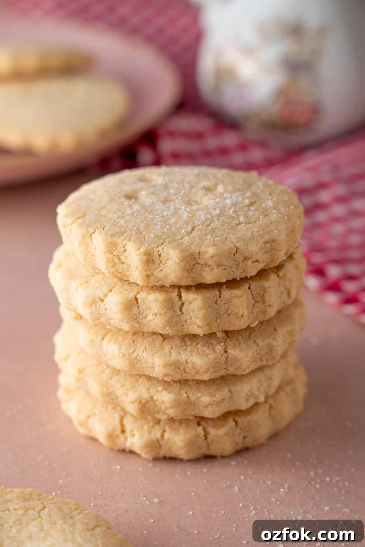 Buttery Gluten-Free Shortbread Cookies Recipe 2 A stack of gluten free shortbread biscuits on a pink worktop.