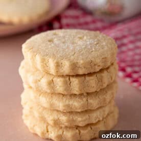 Buttery Gluten-Free Shortbread Cookies Recipe 11 A stack of gluten free shortbread biscuits on a pink worktop.