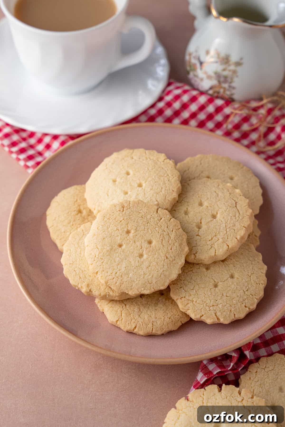 Buttery Gluten-Free Shortbread Cookies Recipe 10 A plate of gluten free shortbread cookies with a cup of tea in the background.