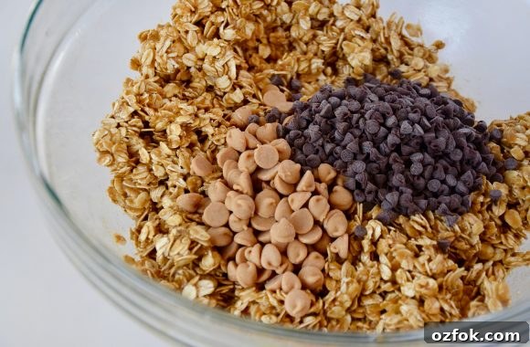 Homemade Peanut Butter Granola Bars Recipe – Chewy No-Bake Snack 5 A glass bowl containing oat mixture with peanut butter chips and mini chocolate chips