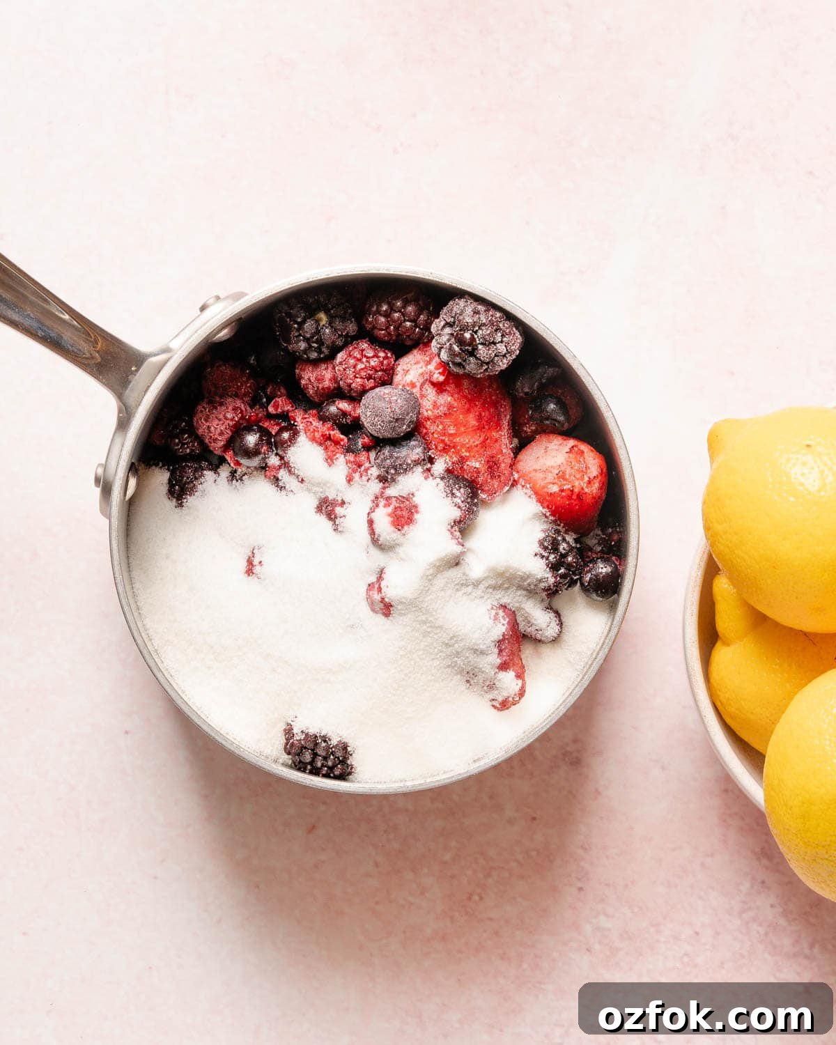 Refreshing Berry Lemonade Recipe: Bright Summer Drink Guide 4 sugar and berries in a pot with lemons on the side.