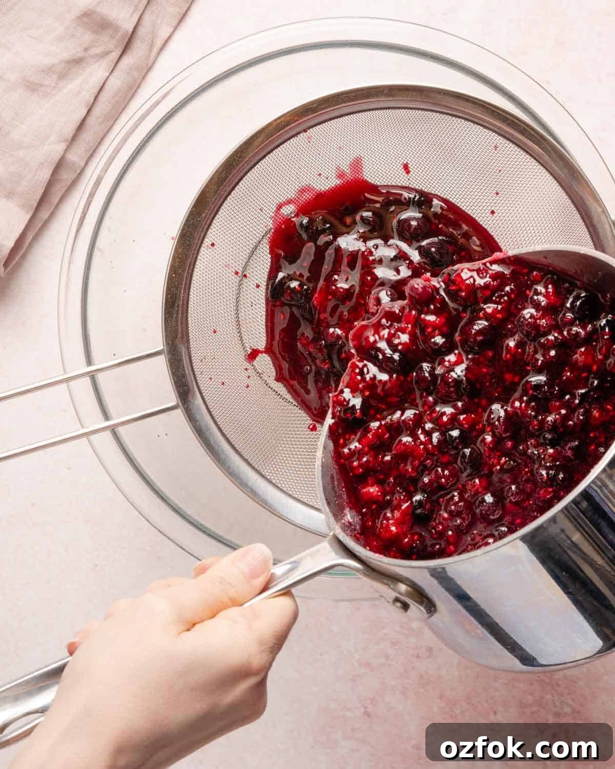 Refreshing Berry Lemonade Recipe: Bright Summer Drink Guide 7 cooked berries being poured into a strainer set over a bowl.