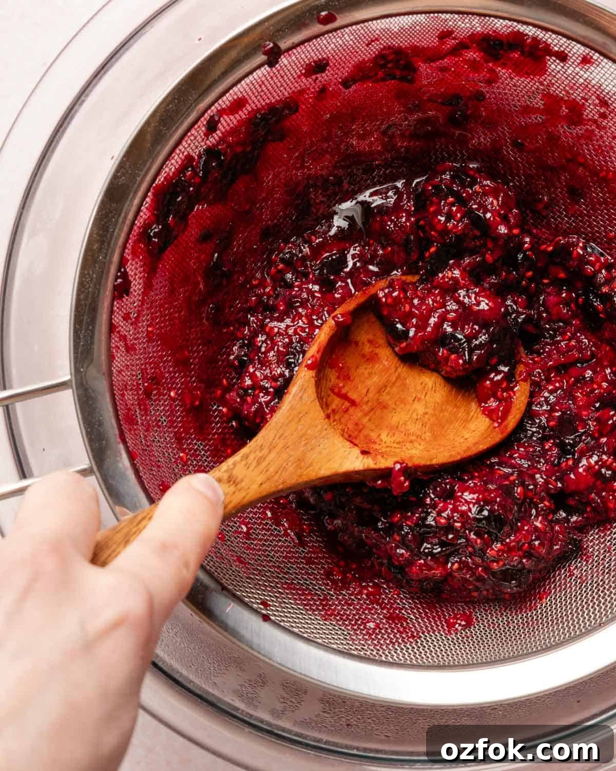 Refreshing Berry Lemonade Recipe: Bright Summer Drink Guide 8 spoon pressing berry pulp through a strainer.