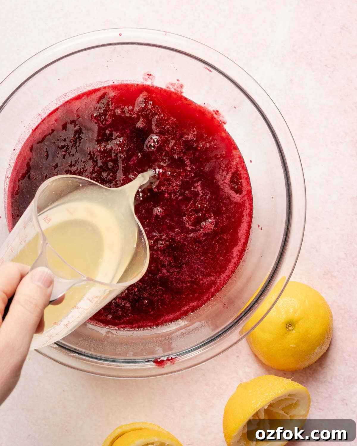 Refreshing Berry Lemonade Recipe: Bright Summer Drink Guide 9 lemon juice being poured into a bowl with berry juice inside.