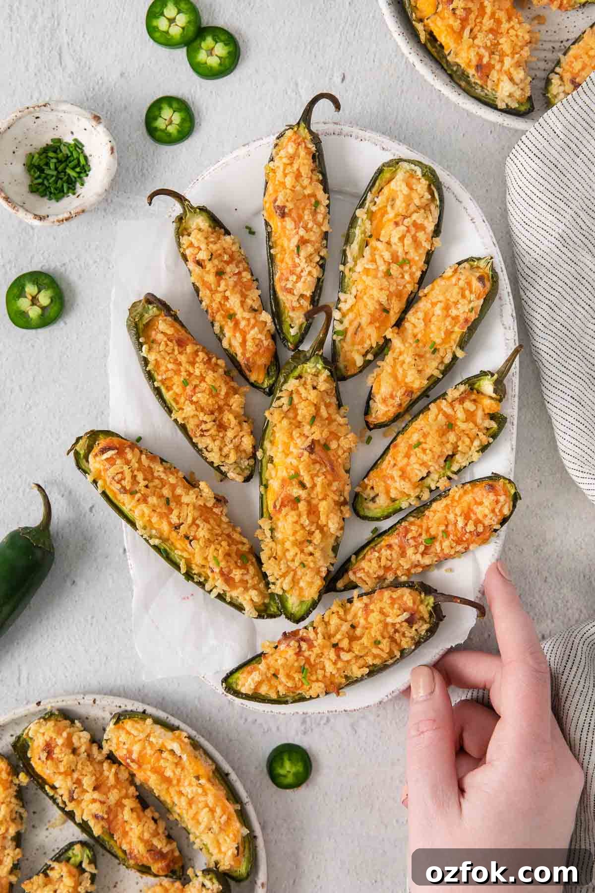 Gluten-Free Jalapeño Poppers Recipe: Crispy Stuffed Peppers 9 Gluten-free jalapeno poppers on a tray with a hand touching the tray