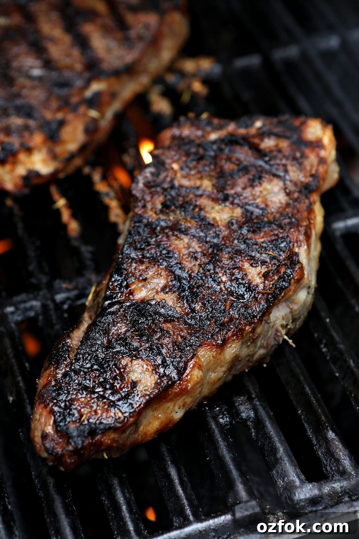 20+ Fourth of July Grilling Recipes for Your Backyard BBQ 14 Two steaks on a grill after flipping