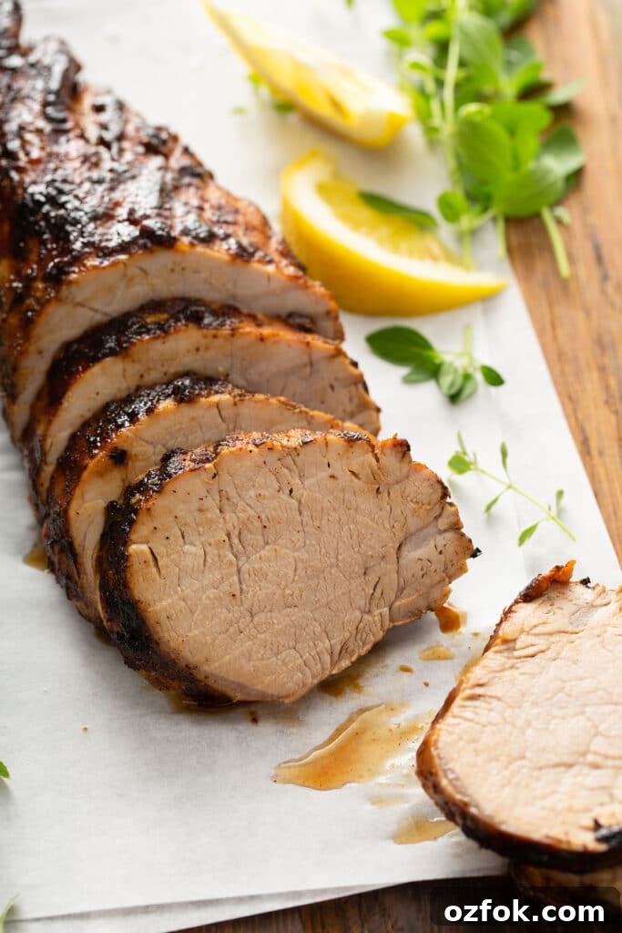 Juicy and tender slices of grilled pork tenderloin on a piece of parchment paper over a cutting board.