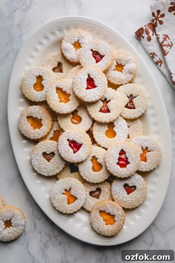Classic Linzer Cookies Recipe: How to Make the Traditional Austrian Jam-Filled Biscuit 2 Linzer cookies on a large white platter.