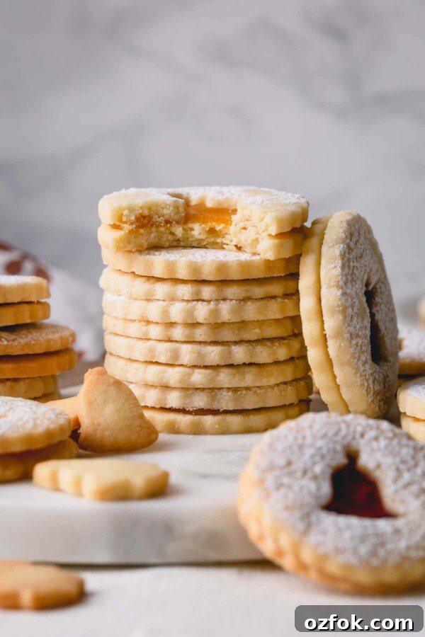 Classic Linzer Cookies Recipe: How to Make the Traditional Austrian Jam-Filled Biscuit 3 Stack of linzer cookies and a bitten cookie.