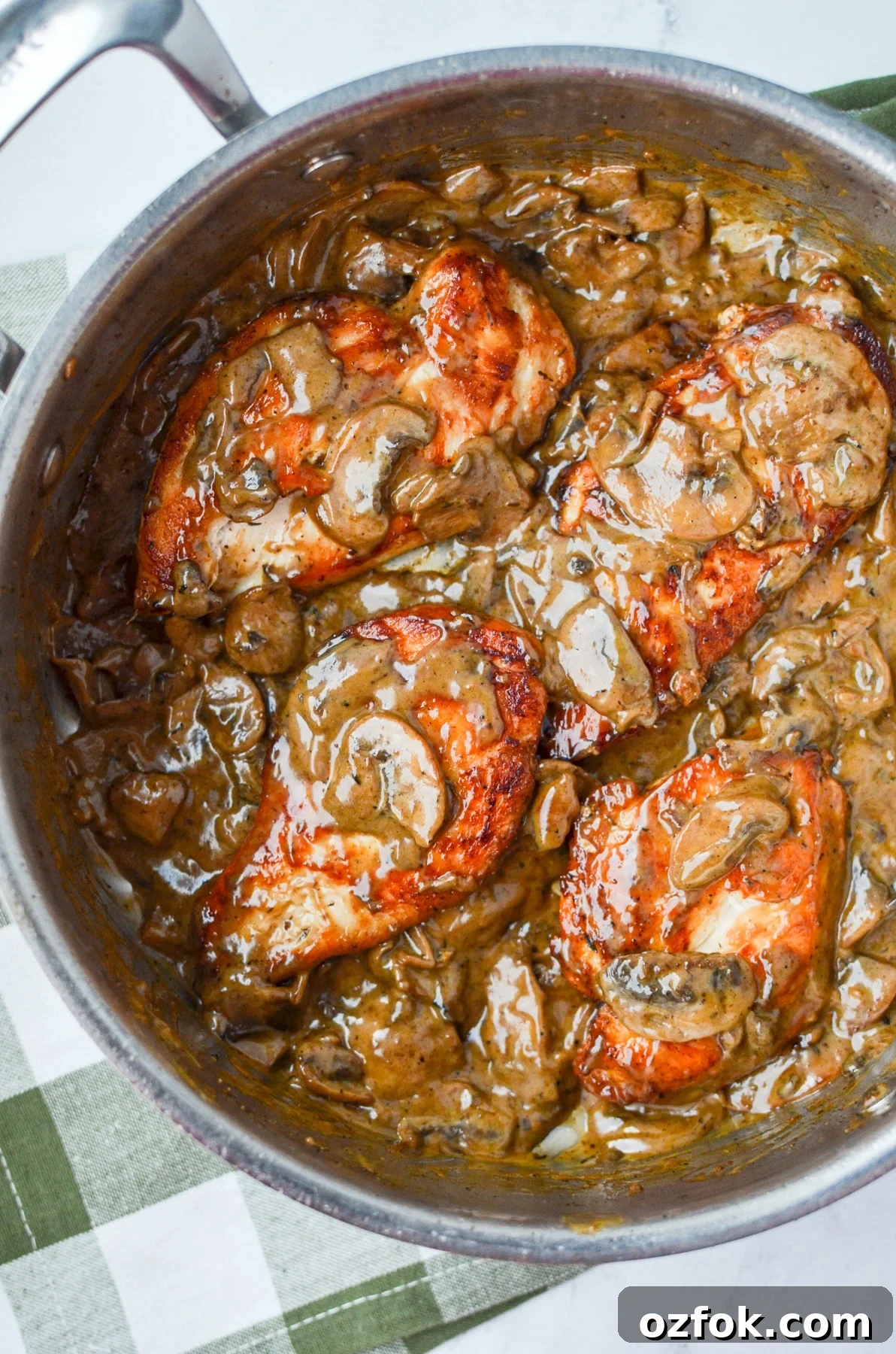 A skillet with chicken breasts and creamy mushroom sauce.