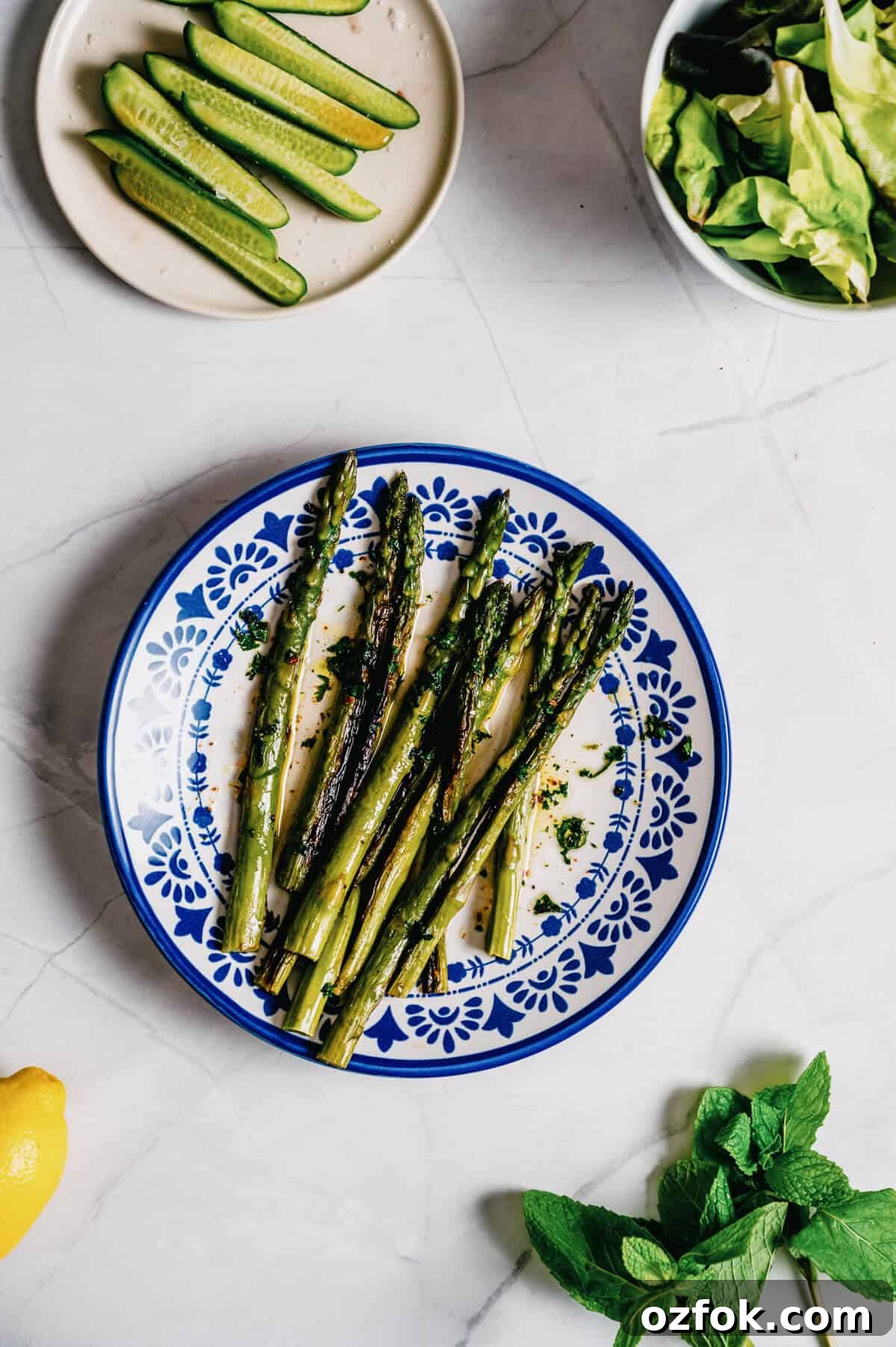 Foil-Grilled Asparagus with Lemon and Garlic 2 a white and blue plate filled with grilled asparagus with cucumbers and salad on the side.