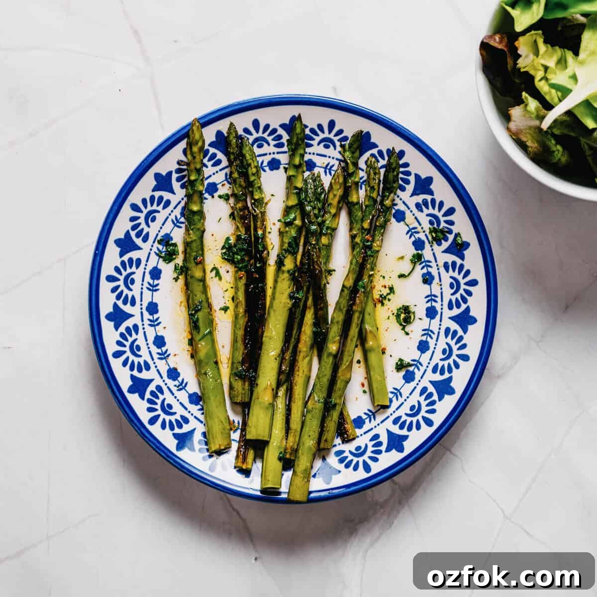 Foil-Grilled Asparagus with Lemon and Garlic 11 a white and blue plate filled with grilled asparagus.