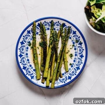 Foil-Grilled Asparagus with Lemon and Garlic 13 a white and blue plate filled with grilled asparagus.