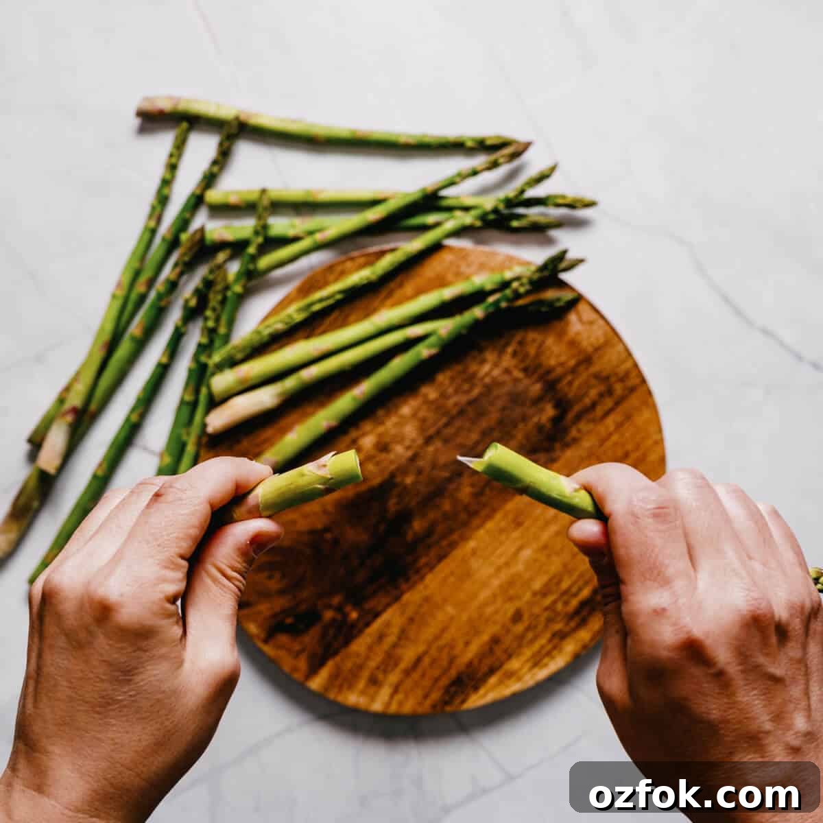 Foil-Grilled Asparagus with Lemon and Garlic 4 a pair of hands snapping the woody ends of asparagus.