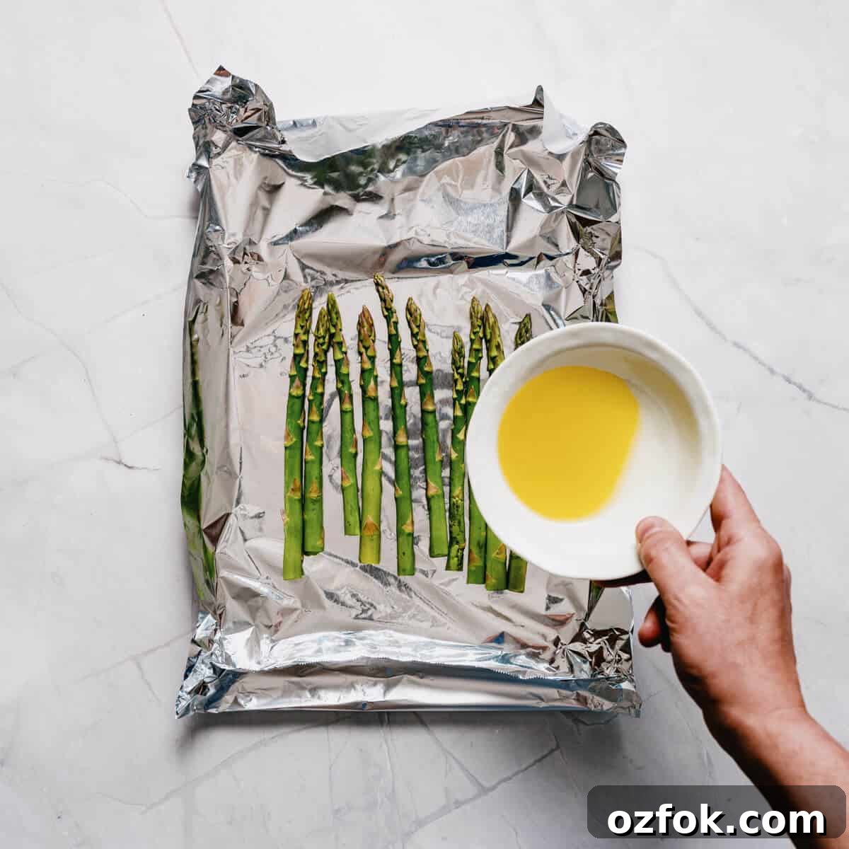 Foil-Grilled Asparagus with Lemon and Garlic 7 drizzling olive oil over asparagus spears in aluminum foil.