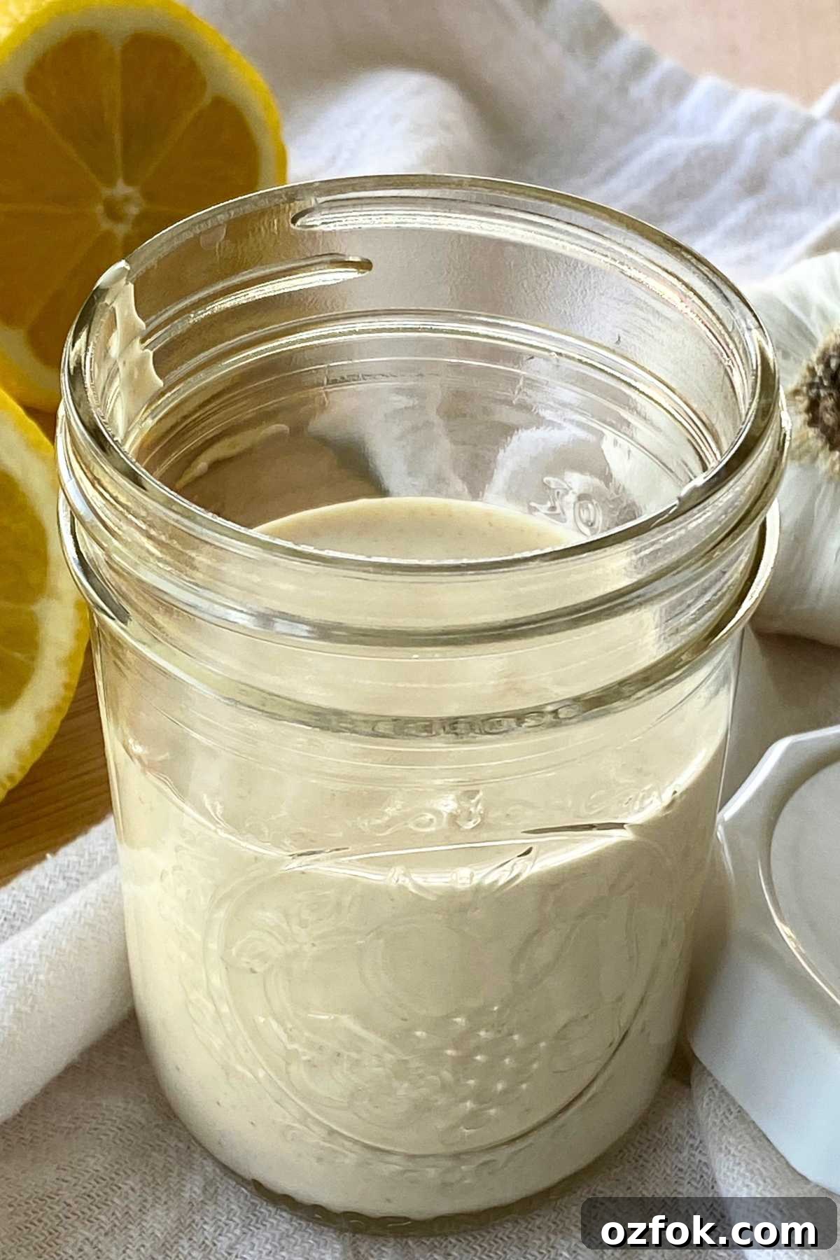 Lemon Garlic Aioli: Homemade Creamy Sauce Recipe 6 Easy lemon garlic aioli sauce in a small mason jar with lid, lemon, and head of garlic next to it.