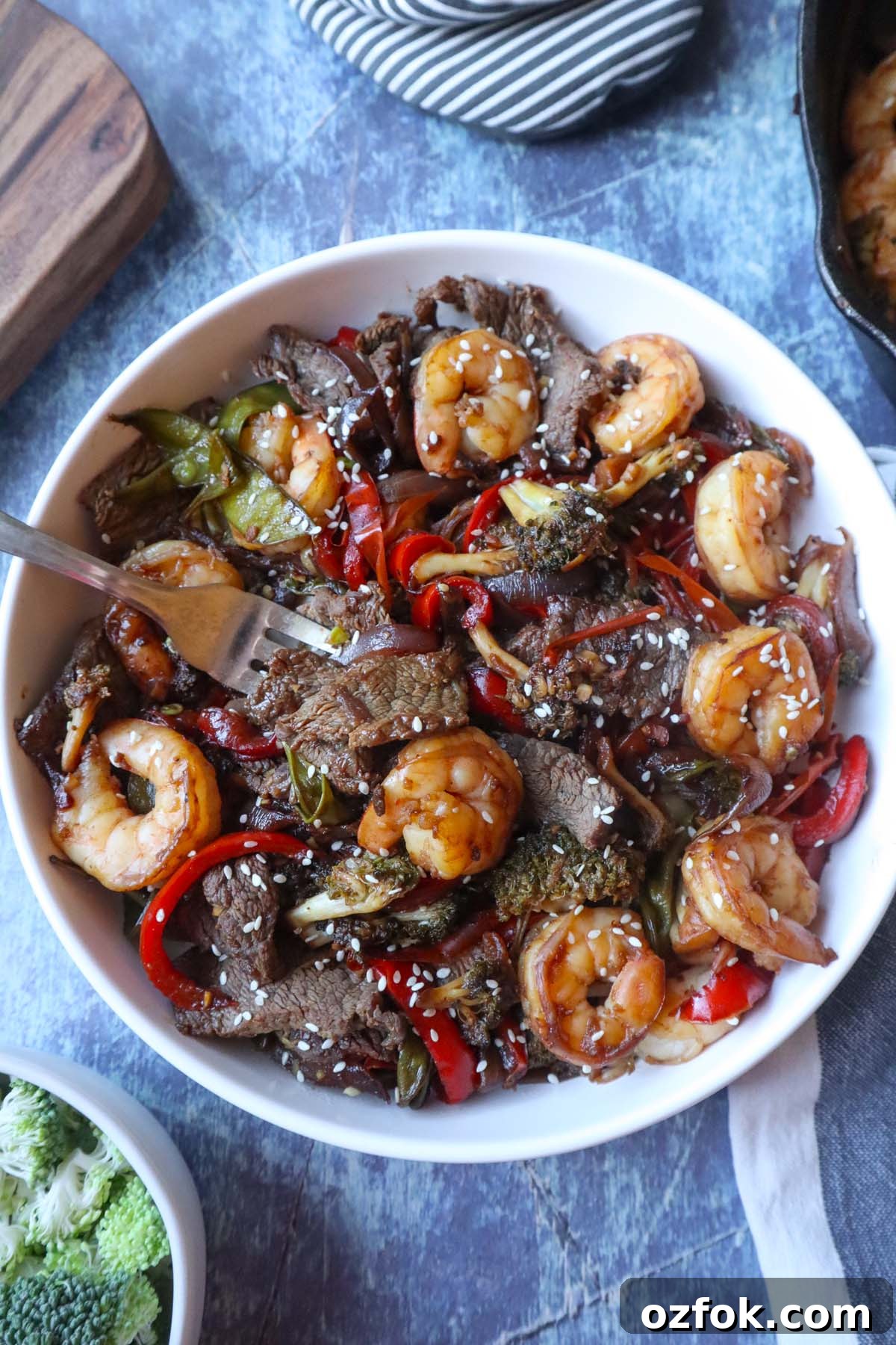 Shrimp and Steak Stir-Fry Recipe for Fast Weeknight Meals 2 white plate with shrimp and steak stir fry topped with sesame seeds