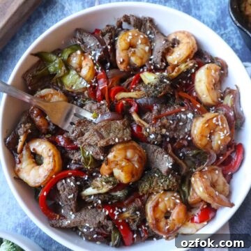 Shrimp and Steak Stir-Fry Recipe for Fast Weeknight Meals 12 white plate with stir fry shrimp and steak topped with sesame seeds
