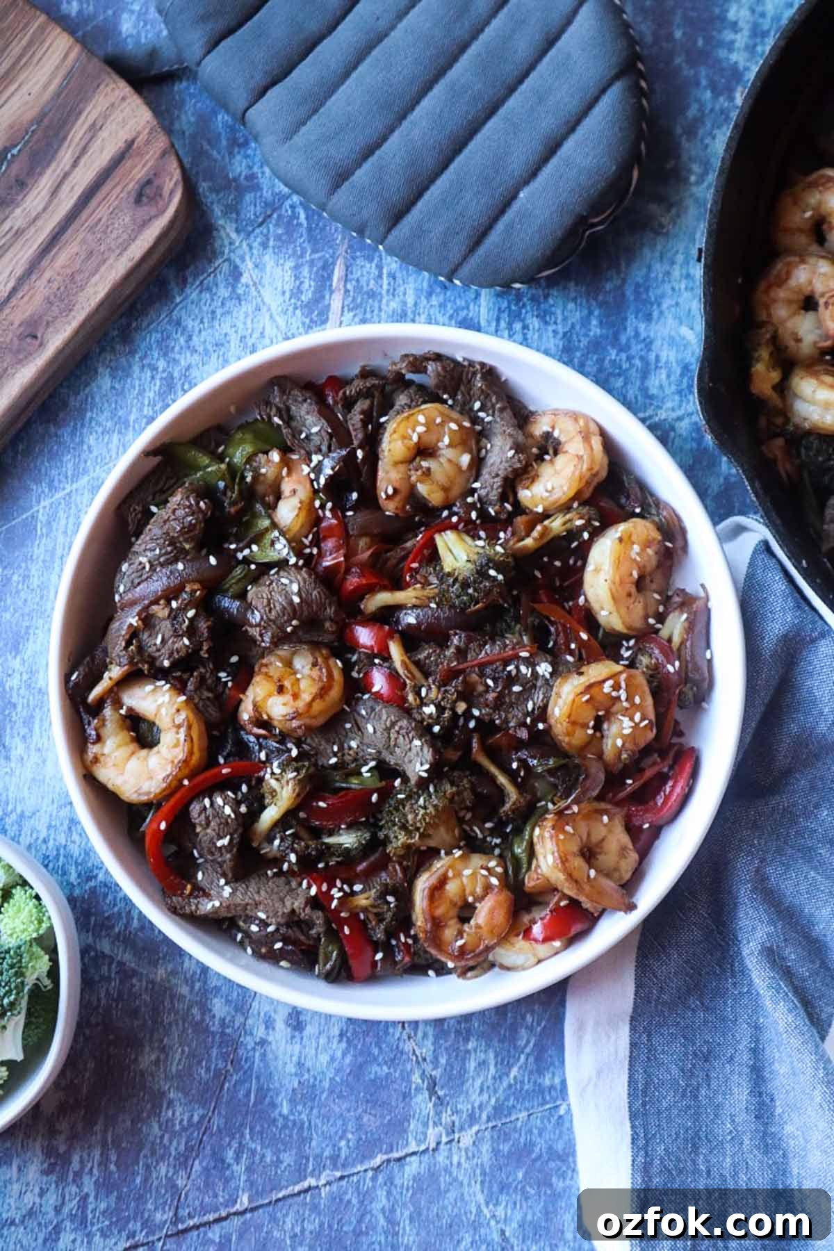 Shrimp and Steak Stir-Fry Recipe for Fast Weeknight Meals 3 white plate with stir fry shrimp and steak topped with sesame seeds