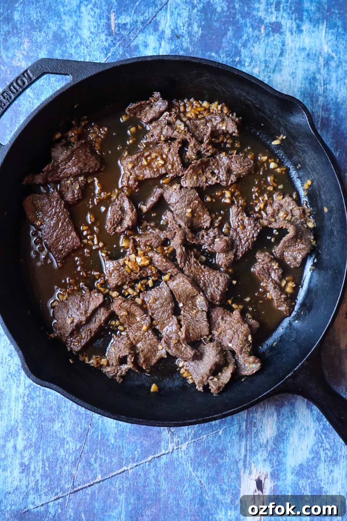 Shrimp and Steak Stir-Fry Recipe for Fast Weeknight Meals 4 cast iron skillet with sliced steak cooked in a garlic stir fry sauce