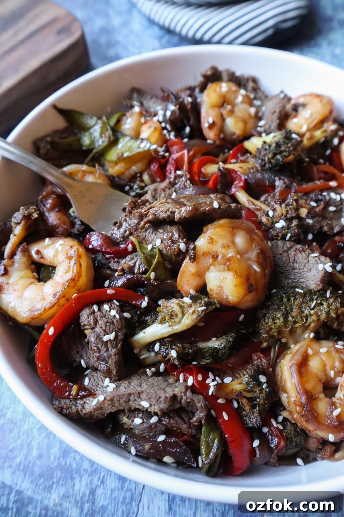 Shrimp and Steak Stir-Fry Recipe for Fast Weeknight Meals 7 white plate with shrimp and steak topped with sesame seeds