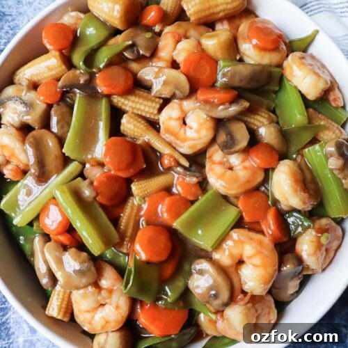 close up of shrimp chop suey in a white bowl with a blue background