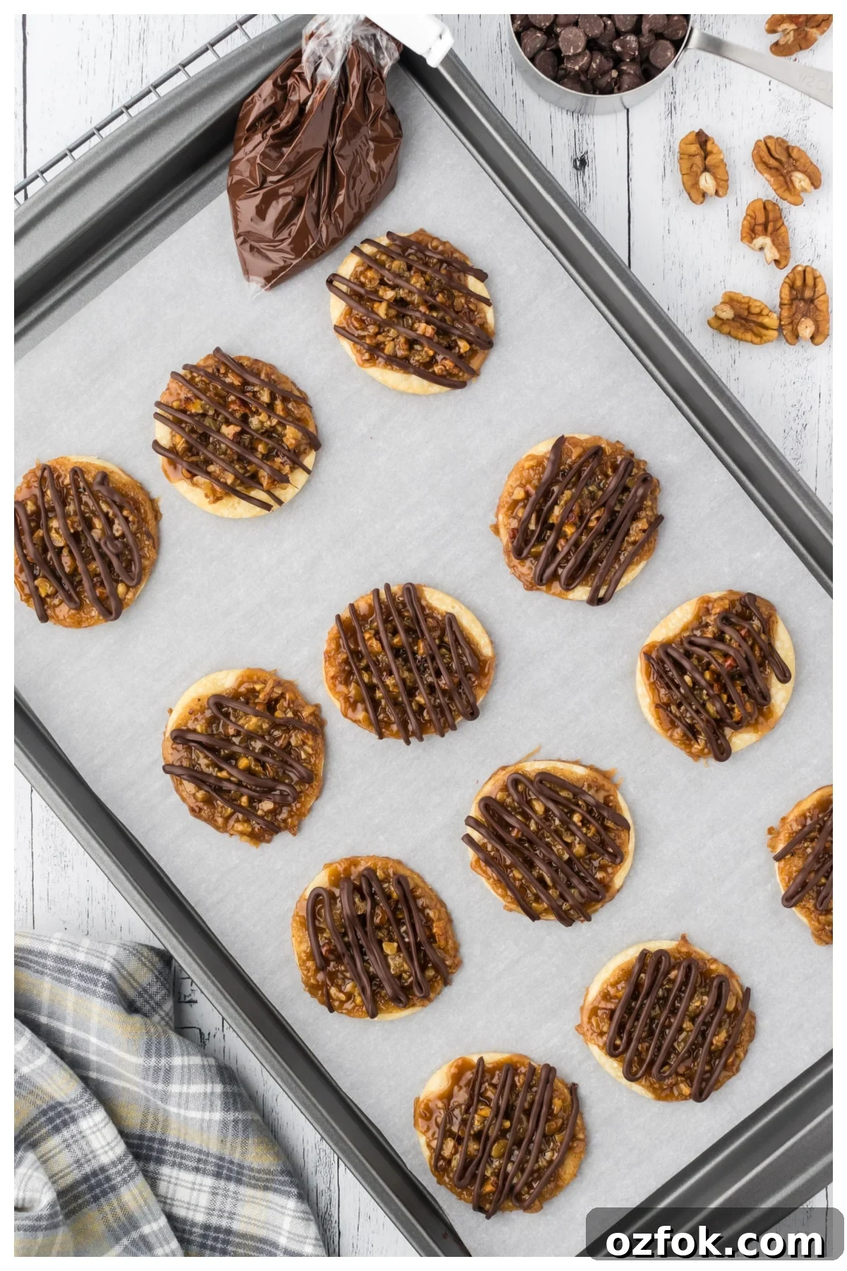 Pecan Pie Cookie Recipe: Chewy Cookies with Cinnamon Glaze 11 Baked cookies on a cookie sheet being decorated with chocolate.
