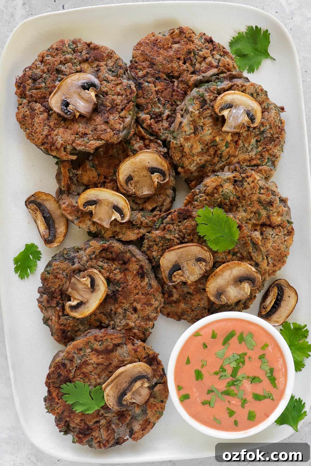 Gluten-Free Miso Mushroom Fritters — Crispy Savory Bites 3 Fritter on rectangle plate. cooked mushrooms and coriander leaves on top of fritters for decoration. Creamy tomato sauce on the side.
