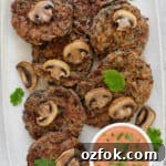 Fritter on rectangle plate. cooked mushrooms and coriander leaves on top of fritters for decoration. Creamy tomato sauce on the side.