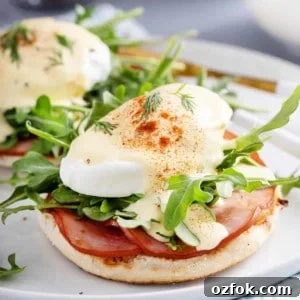 Classic Eggs Benedict Recipe: How to Make Perfect Hollandaise and Poached Eggs 12 Close up of eggs benedict on a white plate.