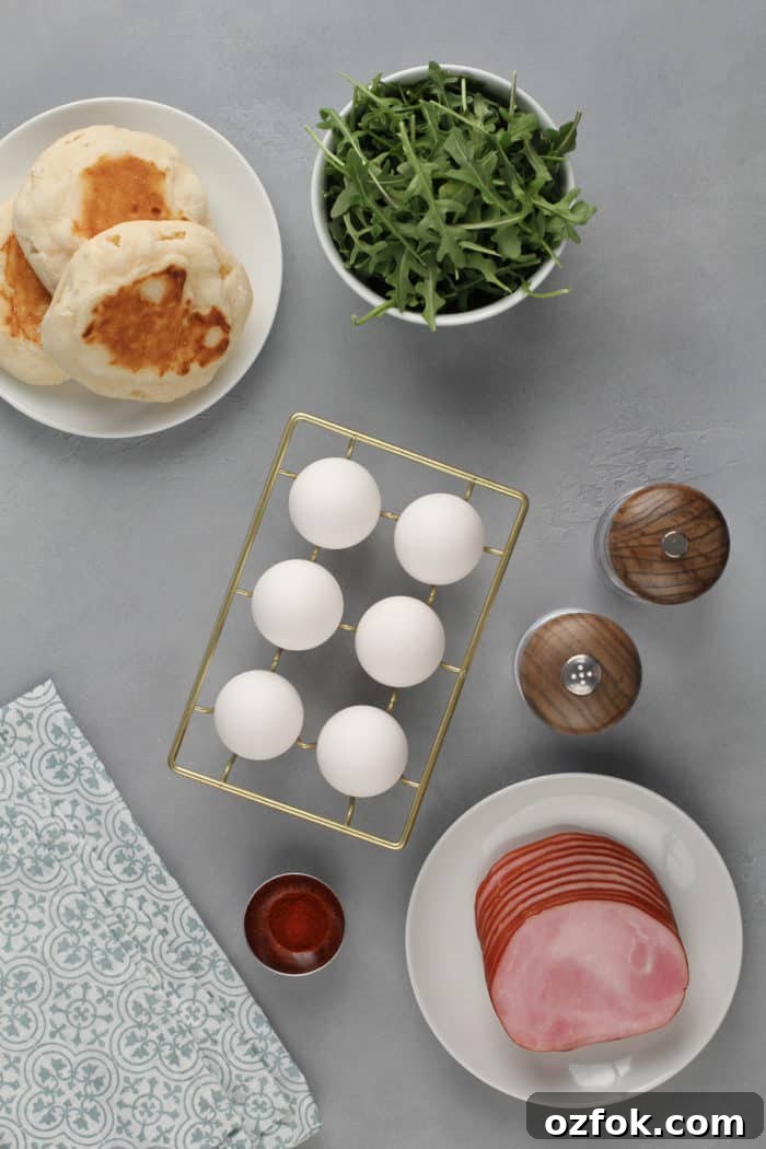 Classic Eggs Benedict Recipe: How to Make Perfect Hollandaise and Poached Eggs 6 Components for eggs benedict arranged on a gray countertop.