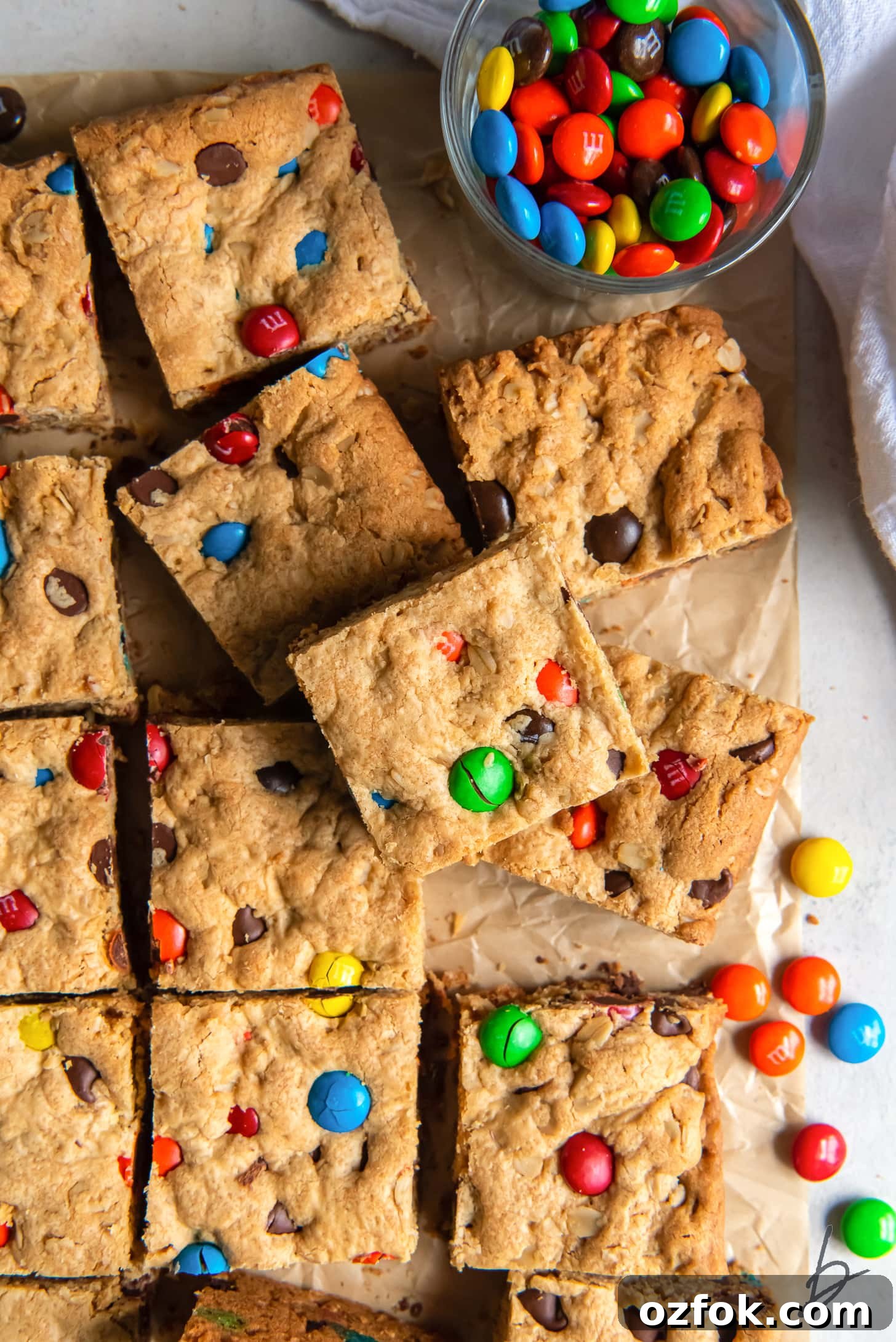 Chewy Monster Cookie Bars Recipe with Chocolate Chips and M&Ms 5 monster cookie bars with m&ms cut into squares.